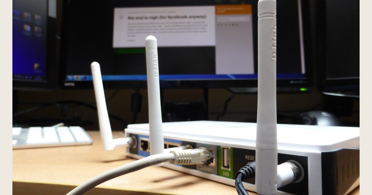 Wireless router with upright antennas in front of computer displays