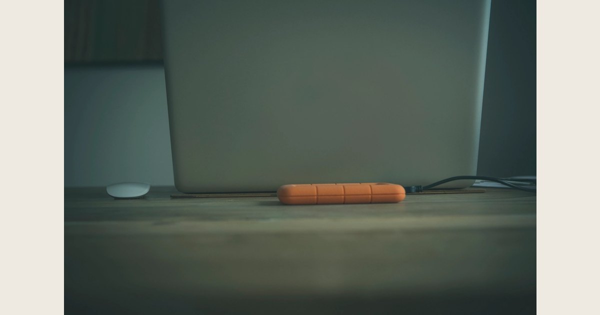 Orange external drive on a desk near a computer