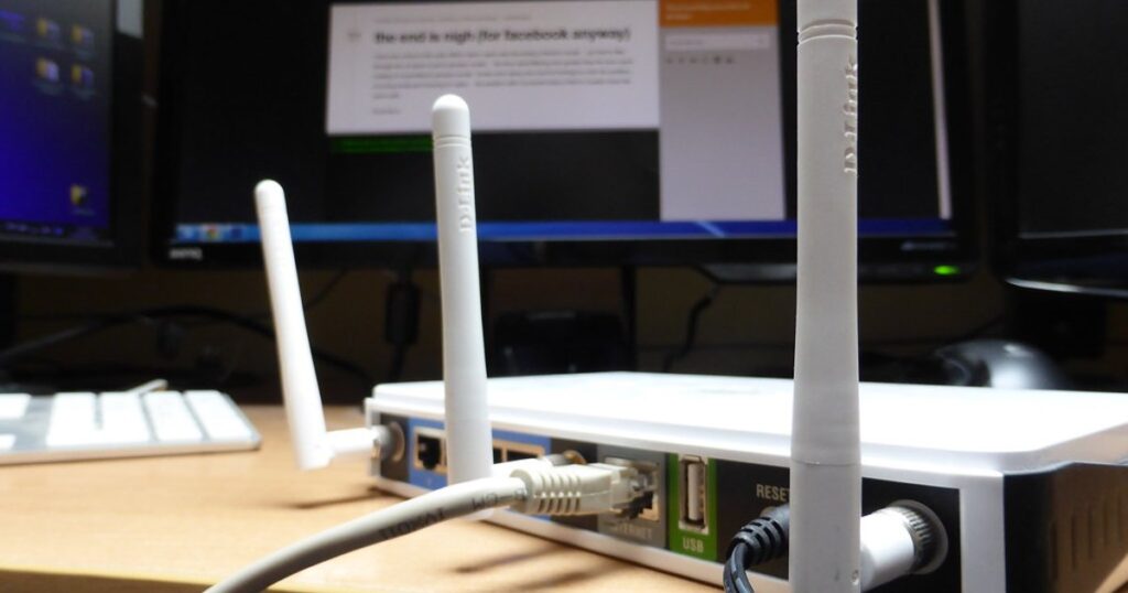 A black wireless router on a wooden desk.